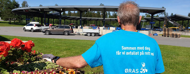 ØRAS ansatt foran rundell med t-skjorte hvor det står "Sammen med deg får vi avfallet på rett vei". Foto. 