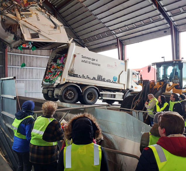 Elever ser på at renovasjonsbil tømmer avfall. Foto. 