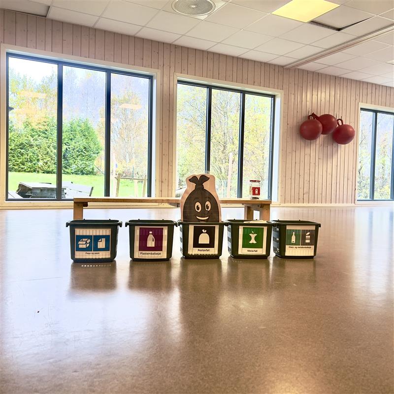 Søppelbøtter med merking av avfallstyper oppstilt på gulv